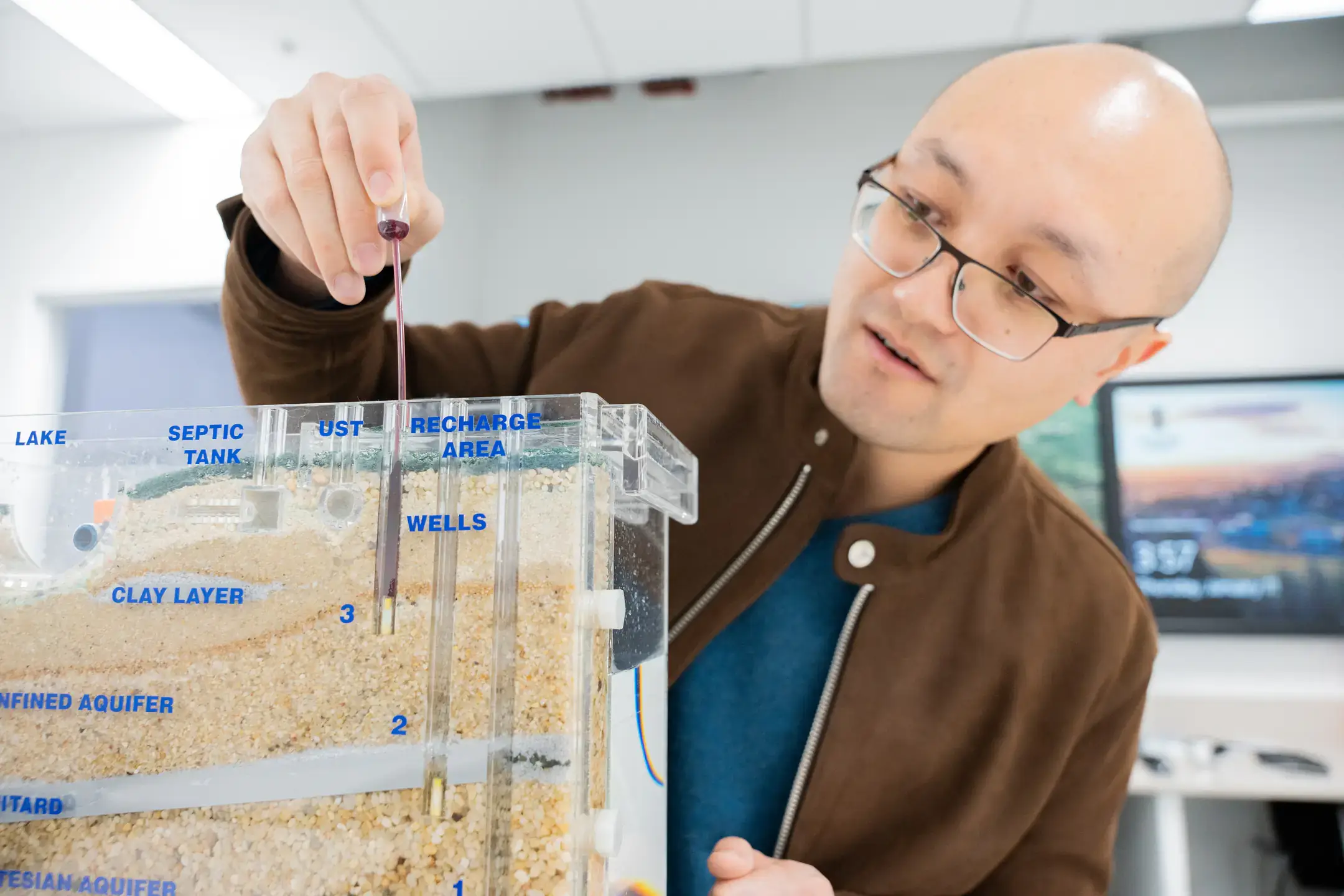 University of Idaho Earth and Spatial Sciences assistant professor  Meng Zhao studies how trees use water in relationship to how much water is available to human beings in relationship with climate change. Here, he is demonstrating a Sand and Gravel ground water Simulator.