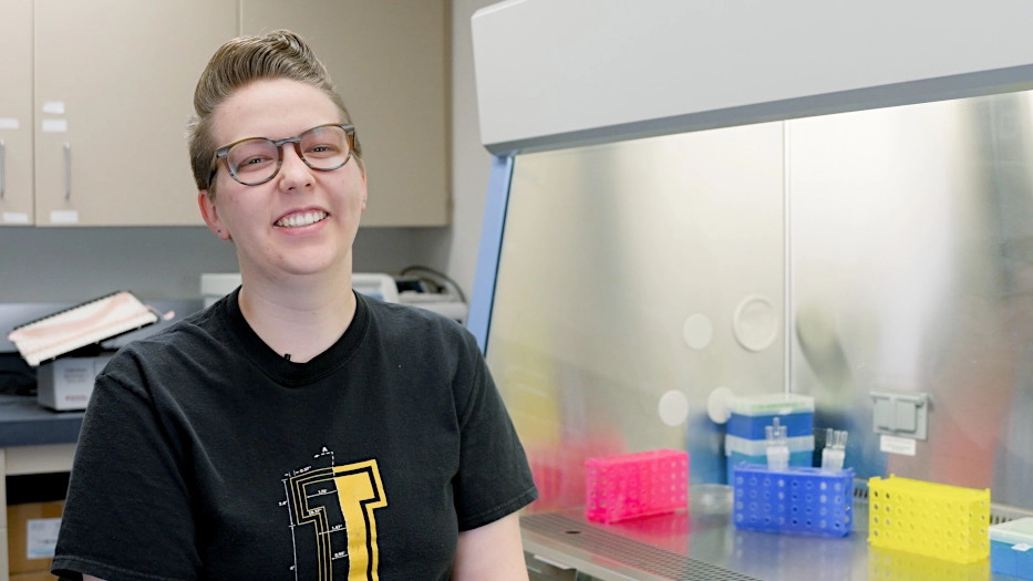 A woman smiling at the camera while being inside a science lab