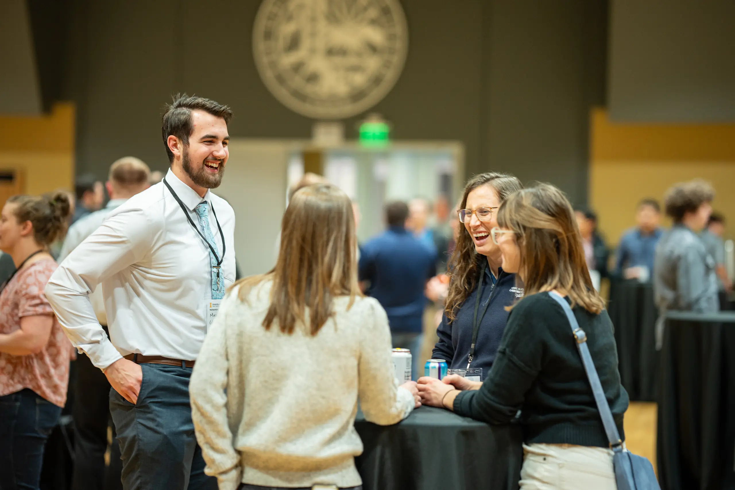 Three women and one man laughing over a table.