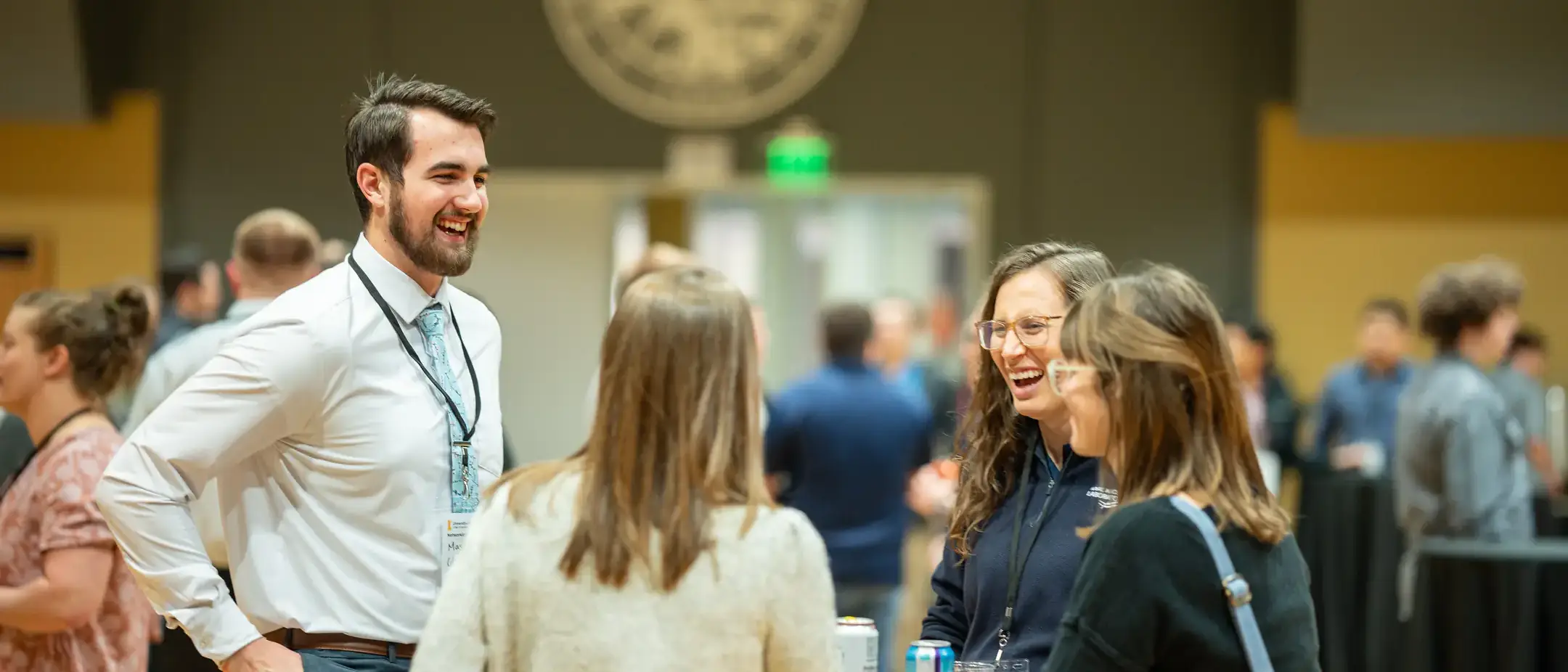 Three women and one man laughing over a table.