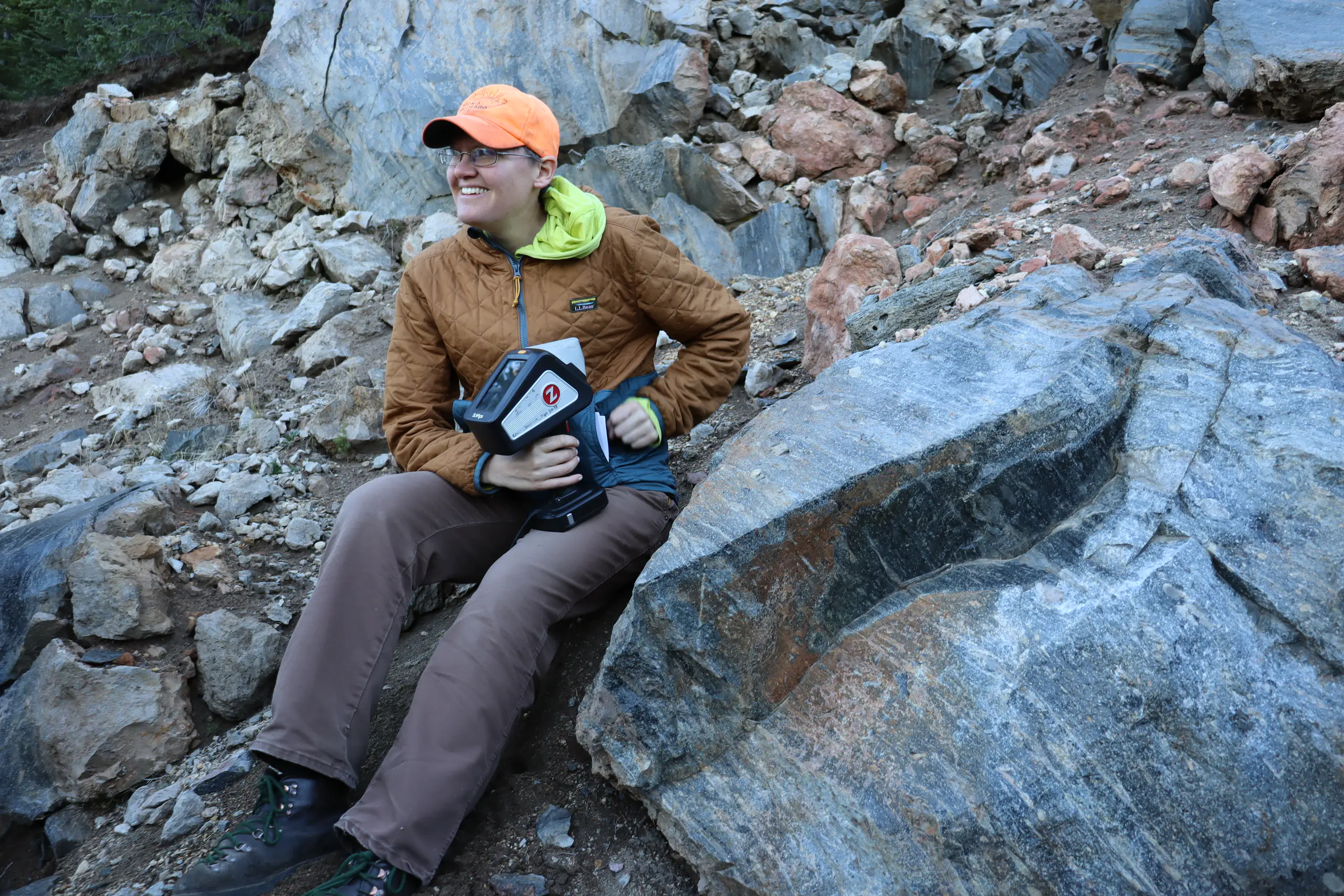 Erika Radar sits next to a rock formation.
