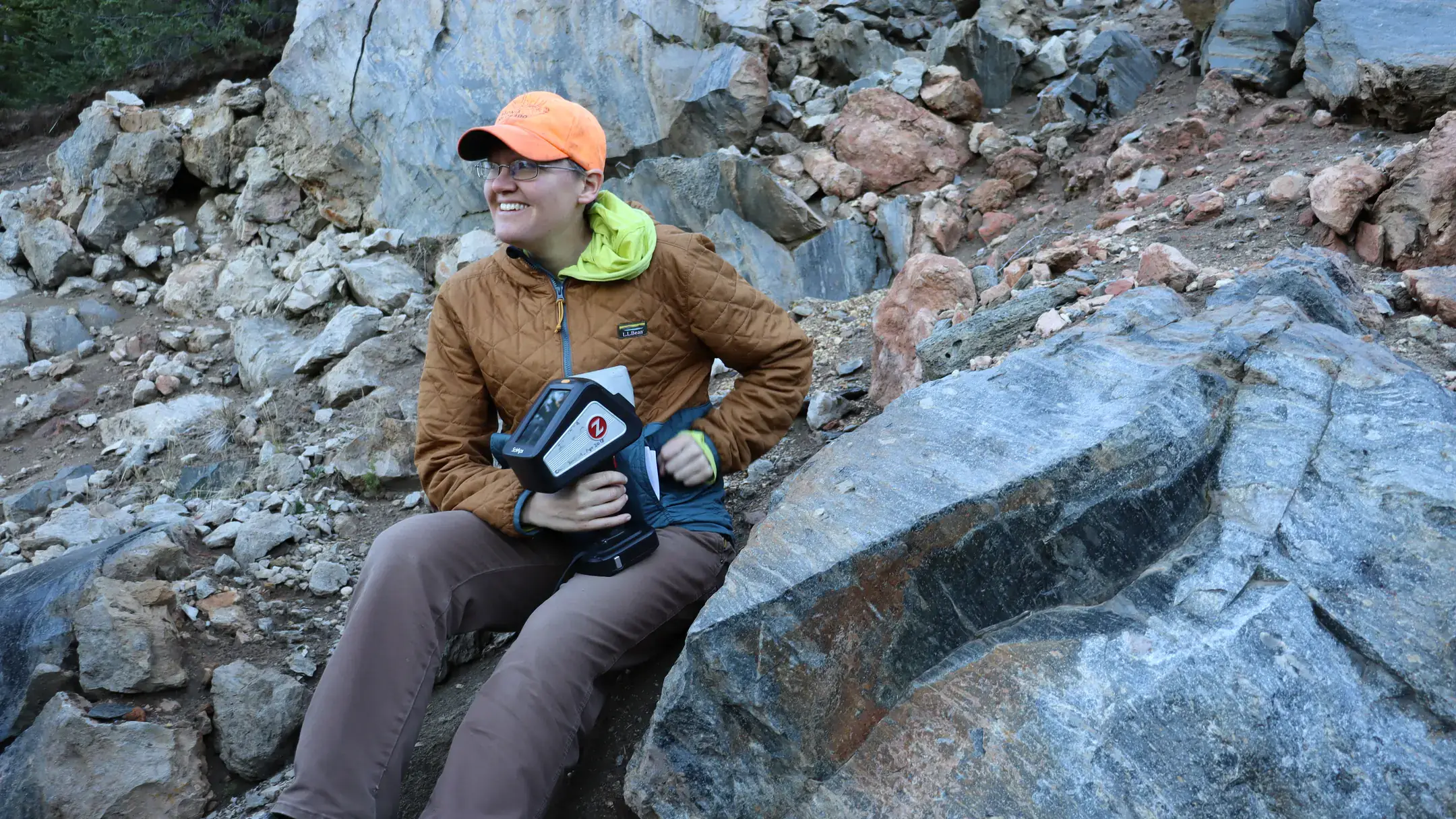 Erika Radar sits next to a rock formation.