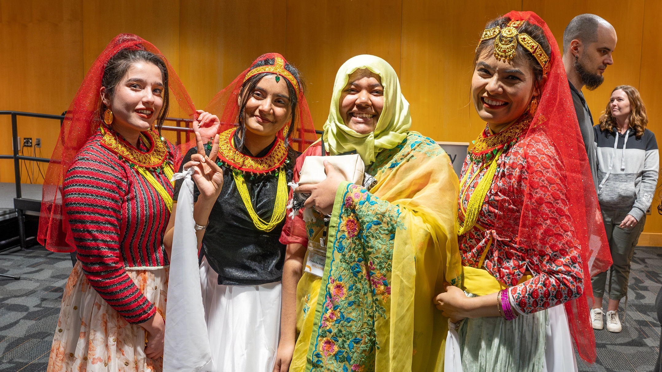 Four women smile while wearing cultural attire