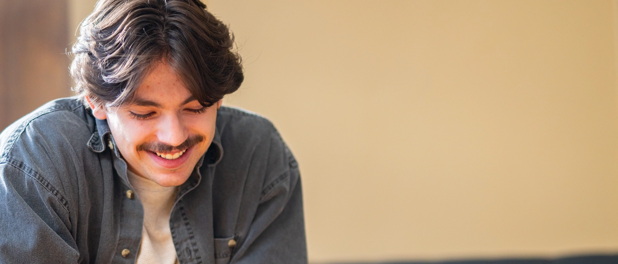 Graduate student Wade Scott smiles sitting at a table in the Department of Psychology and Communications.