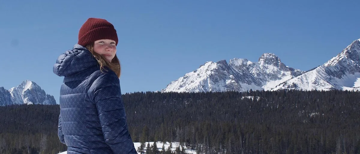 Photo of woman on ski hill with mountain in background.