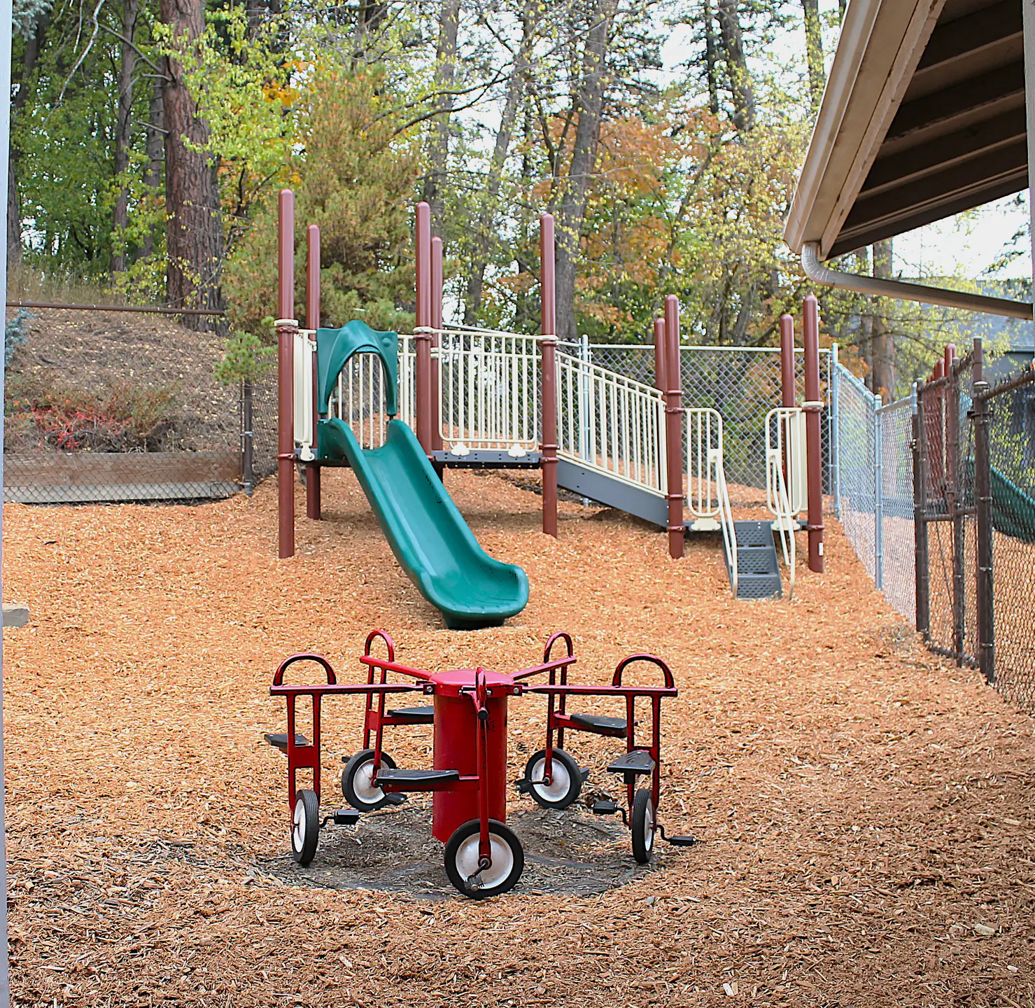 A playground with large jungle gym and small merry-go-round