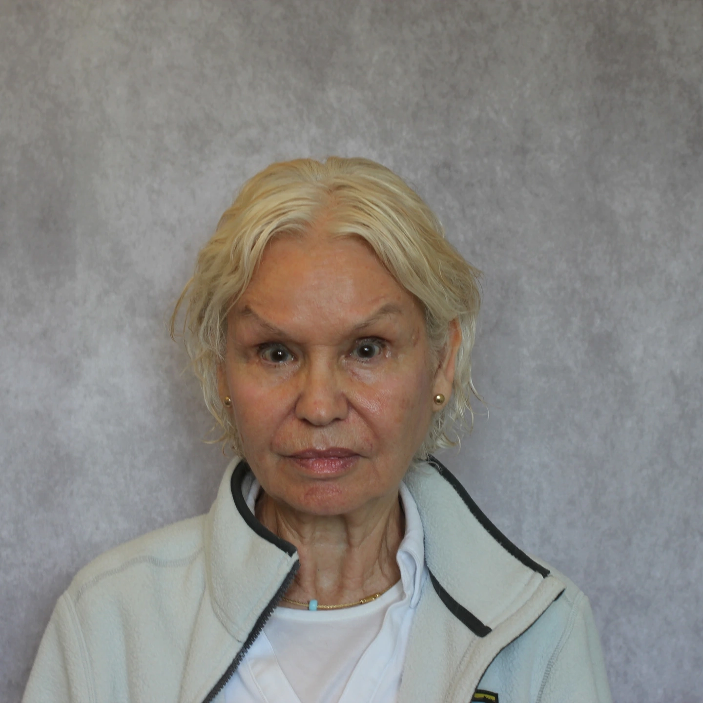 A portrait of a woman standing in front of a grey background.