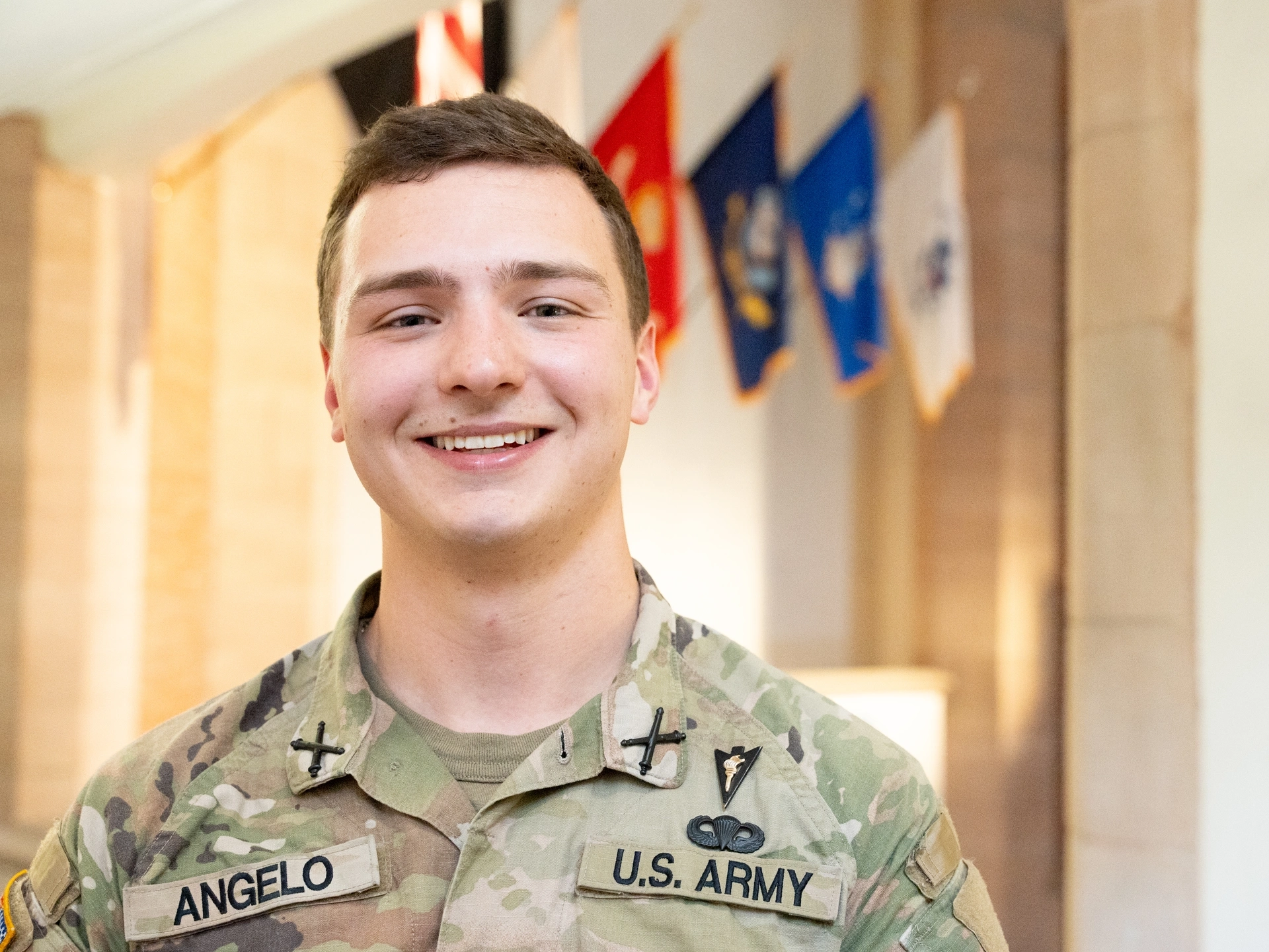 Short-haired man wearing military cammies smiles.