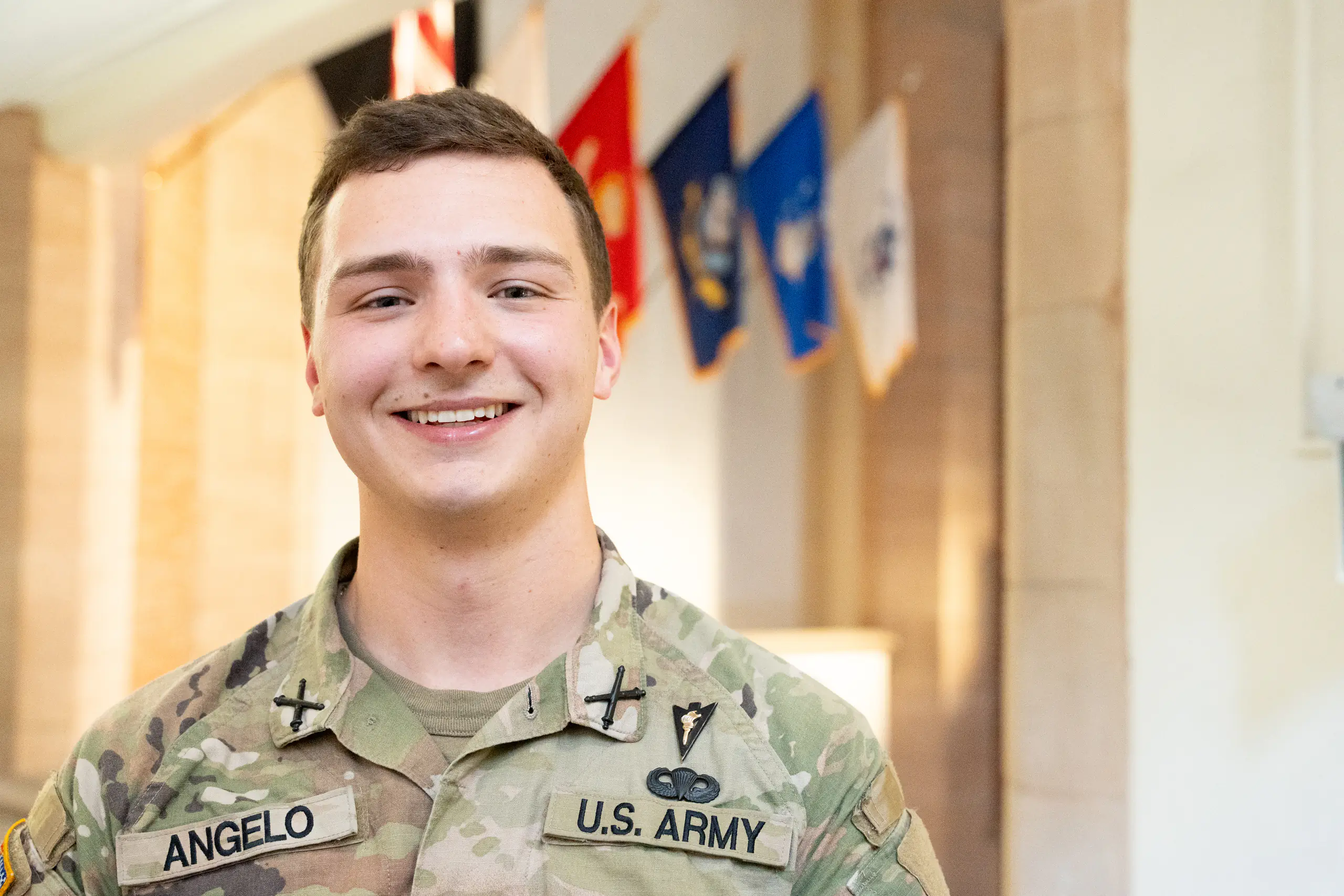 Short-haired man wearing military cammies smiles.