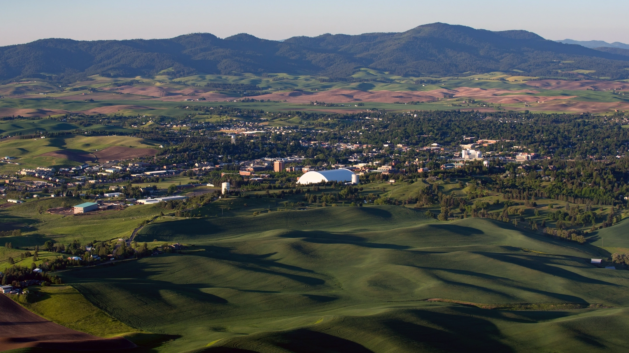 Aerial view of Moscow, ID with lush greenery and mountains in the background