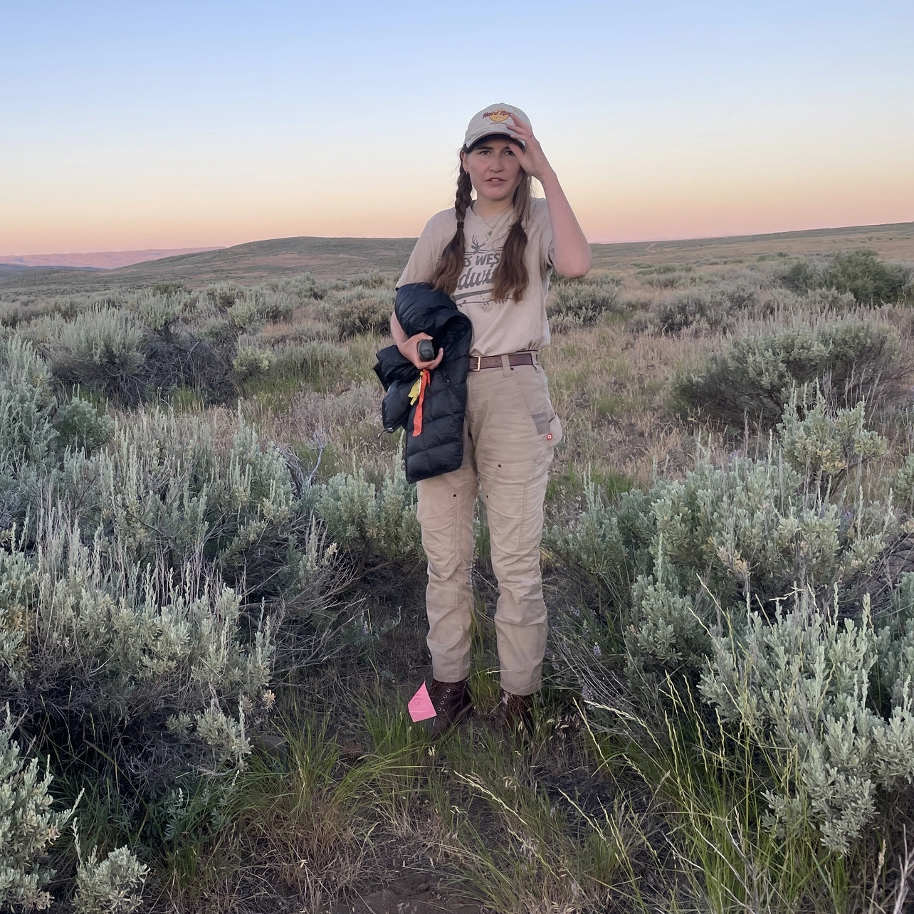 A woman stands by a flag marking the location of a rodent trap she set out in the sagebrush-covered hills at University of Idaho’s Rinker Rock Creek Ranch.