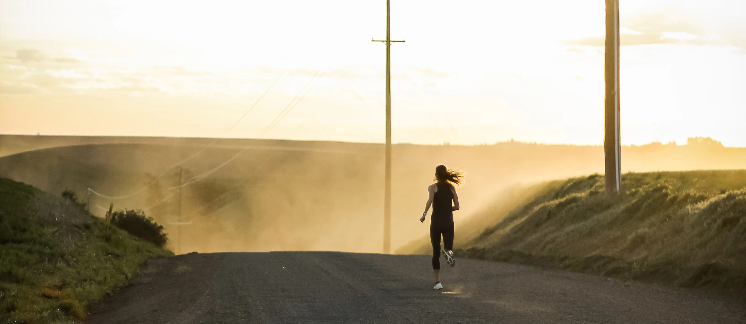 Samantha Lewis runs along a dusty road at sunset.