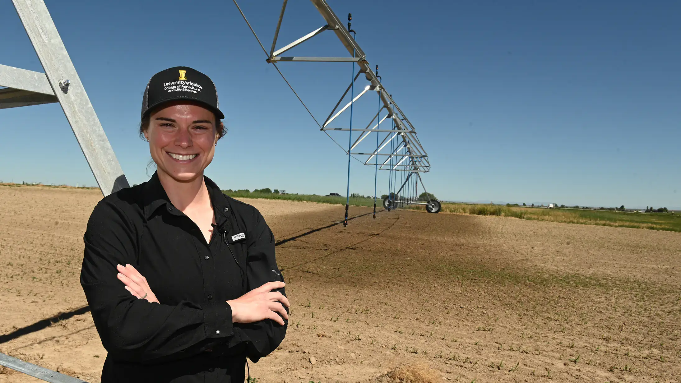  A woman stands by a center pivot in a farm field.