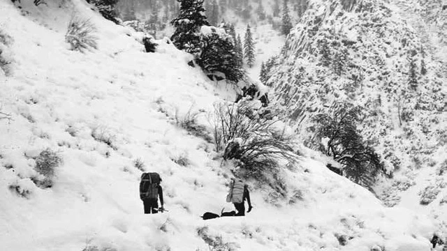 Two people walk through a mountainous landscape