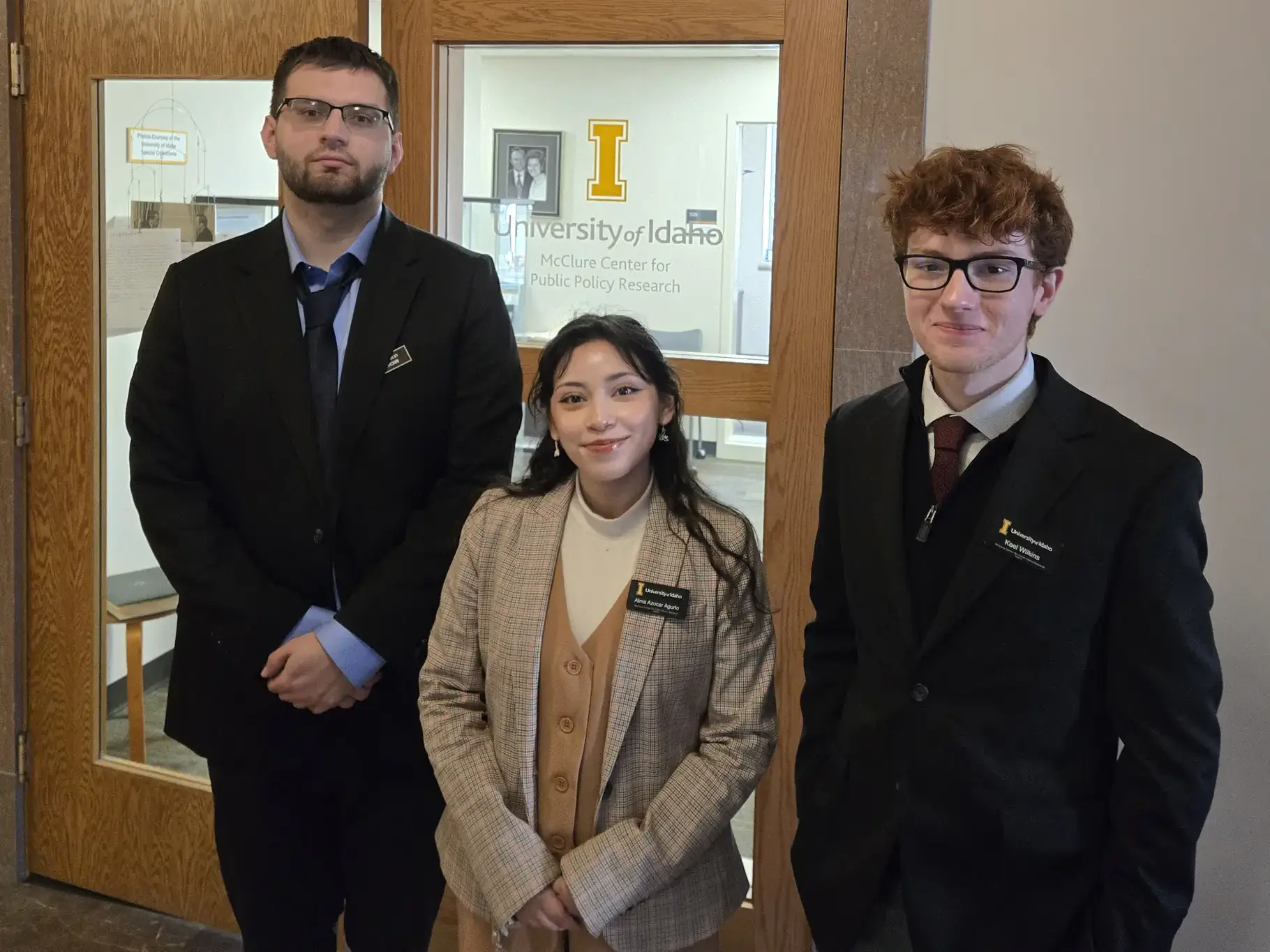 Three students stand in a group in front of McClure Center doors.