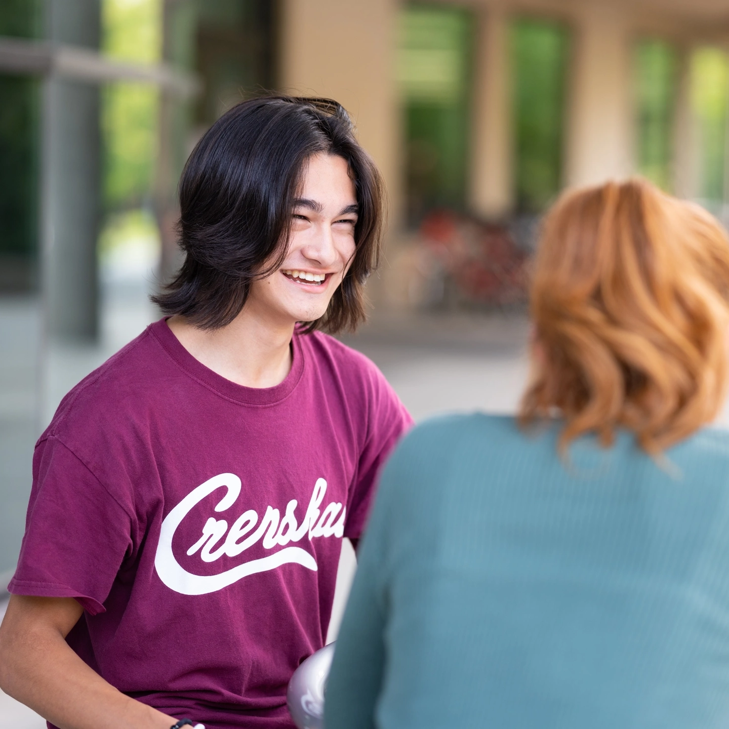 Ӱֱ student in the outdoor seating area in Ӱֱ Library plaza.
