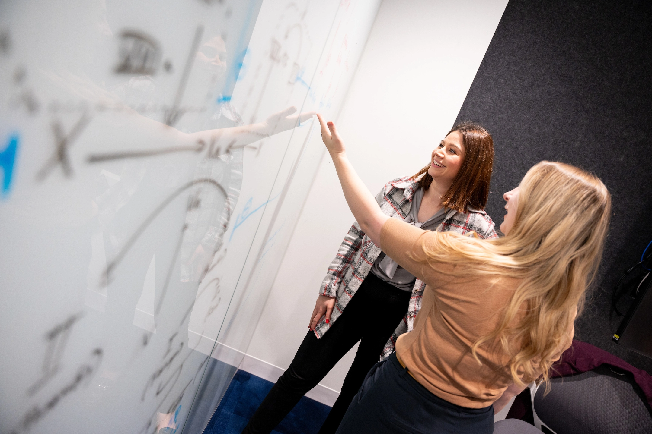 Two students work at a whiteboard.