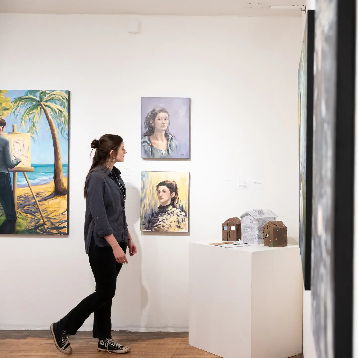 BFA/MFA2 Exhibition with students and student work in the Ridenbaugh Gallery. Pictured is Ashleigh Streiff admiring the artwork on display.