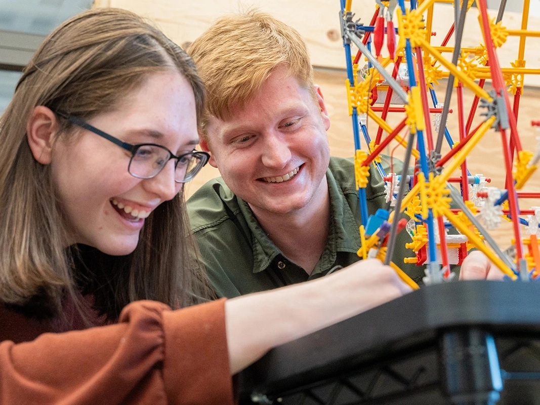 A man and woman study a miniature Ferris wheel. 
