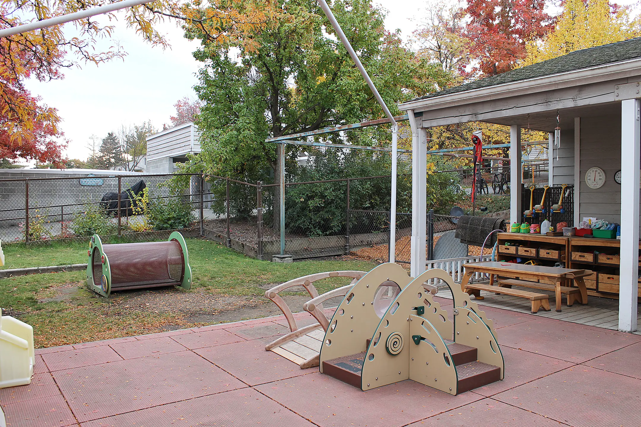 A fenced yard and patio with larger toys for infants and toddlers.