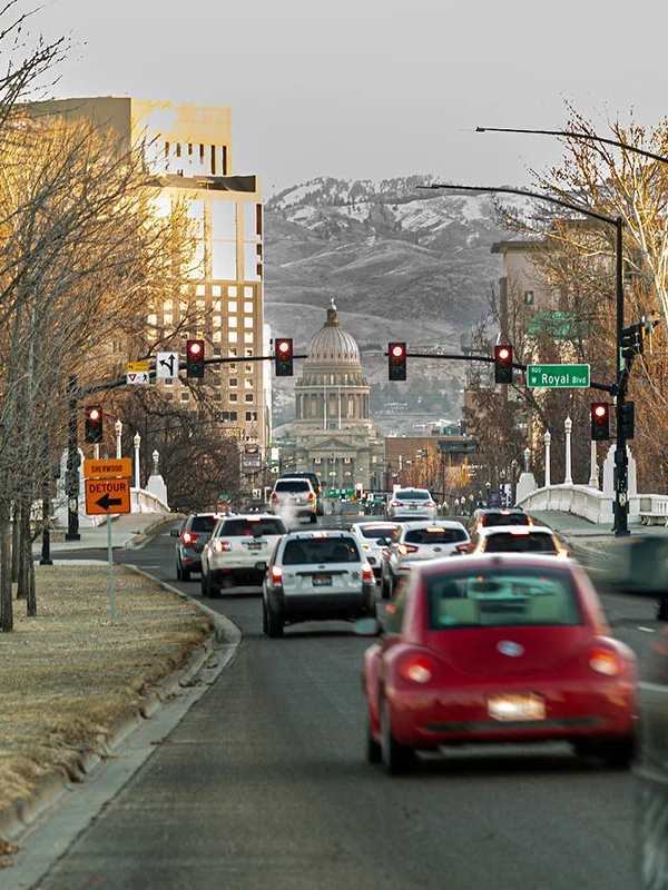 Cars, in motion blur, drive down a street in downtown Boise with the state Capitol at the end.