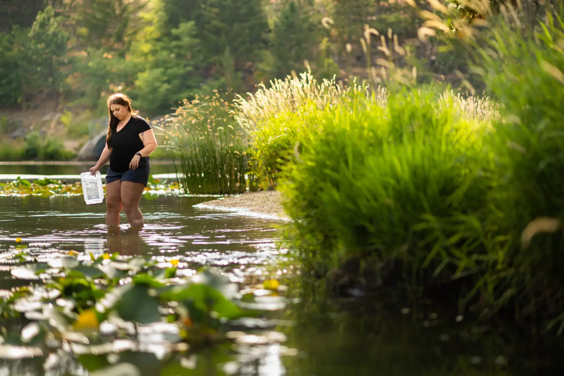 Girl standing in lake, gathering water samples
