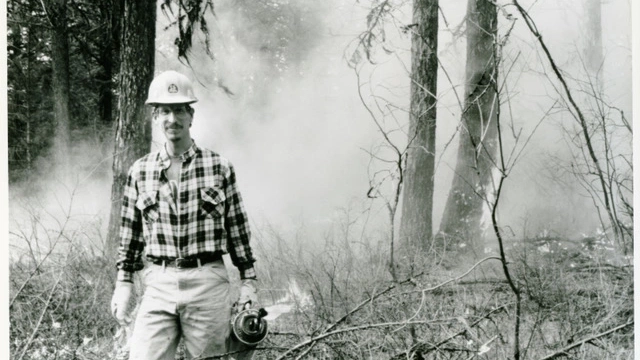 A man stands in front of a ground fire