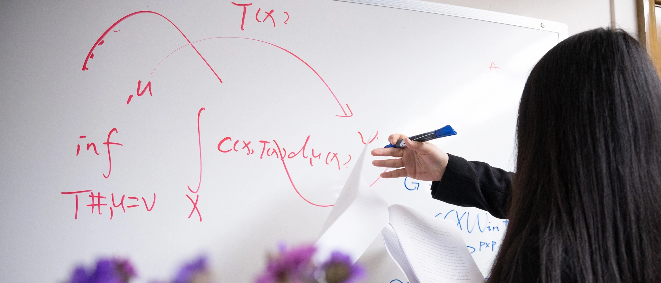 University of Idaho Mathematics and Statistical Science faculty Tiantian Yang uses a white board to work on mathematical models of diseases that can reduce health care costs and that can be easy to interpret so they are trusted by healthcare workers.