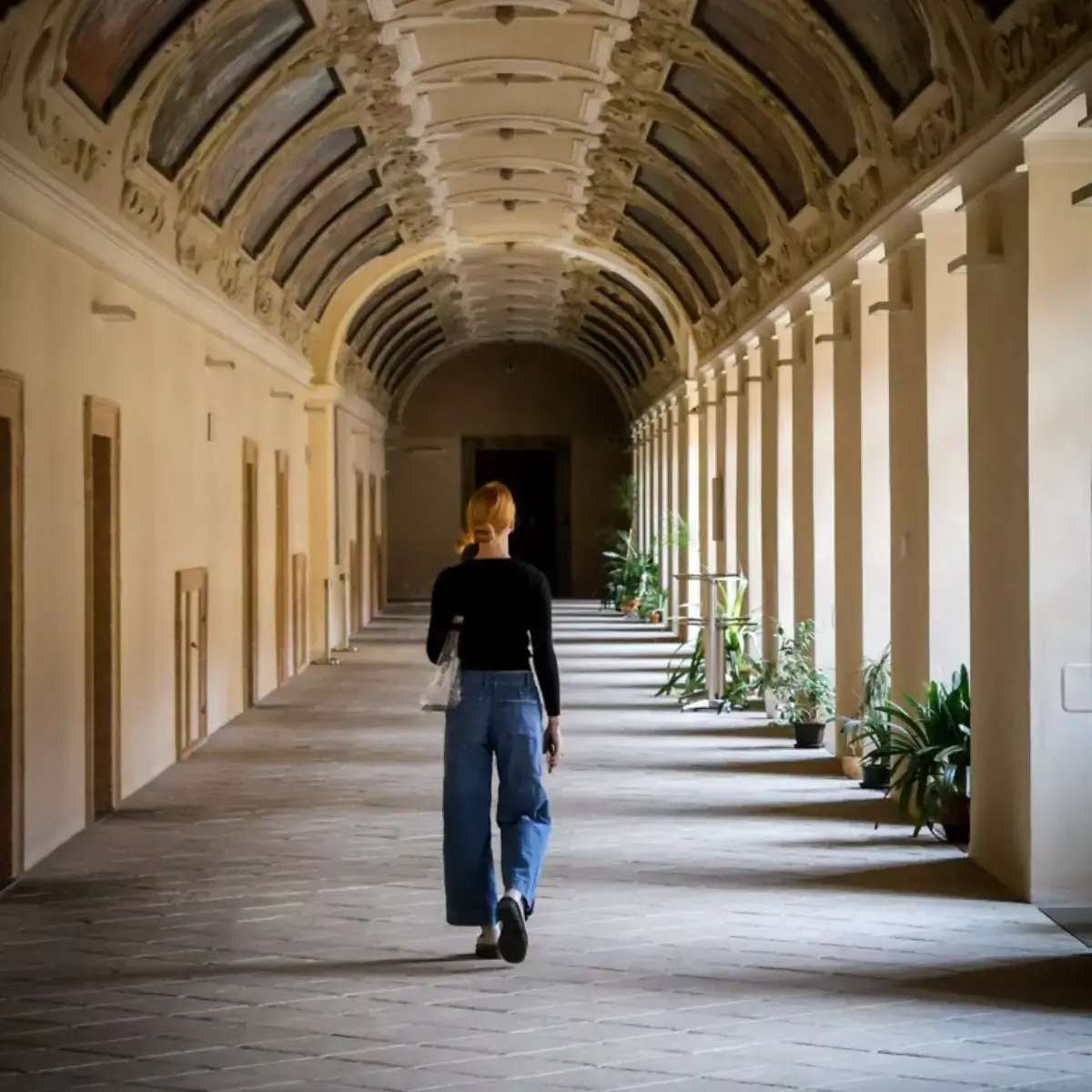 A woman walking through an outdoor hallway.