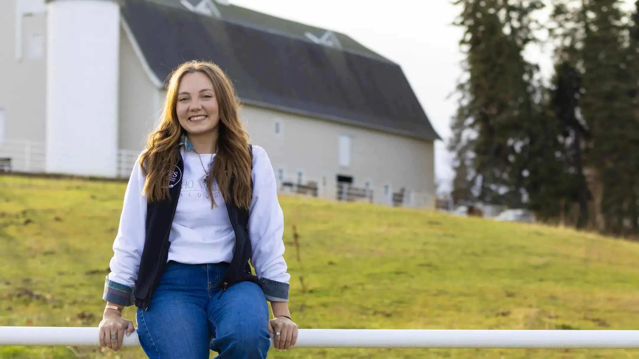  Ady Perkes sits on a fence with the West Barn in the background.