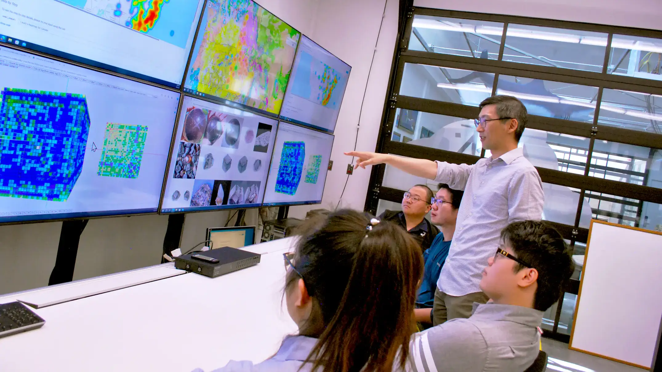 A man teaches students in front of screens.