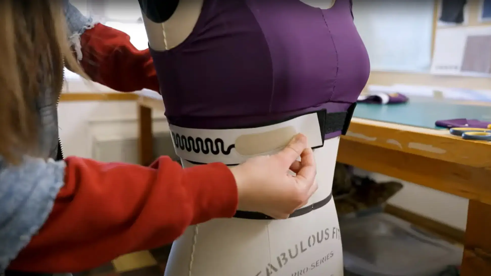 A woman applying a biosensor to a bra top