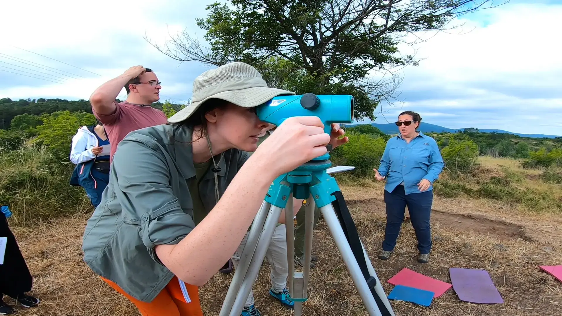 Person looks through a transit at an archeology dig site