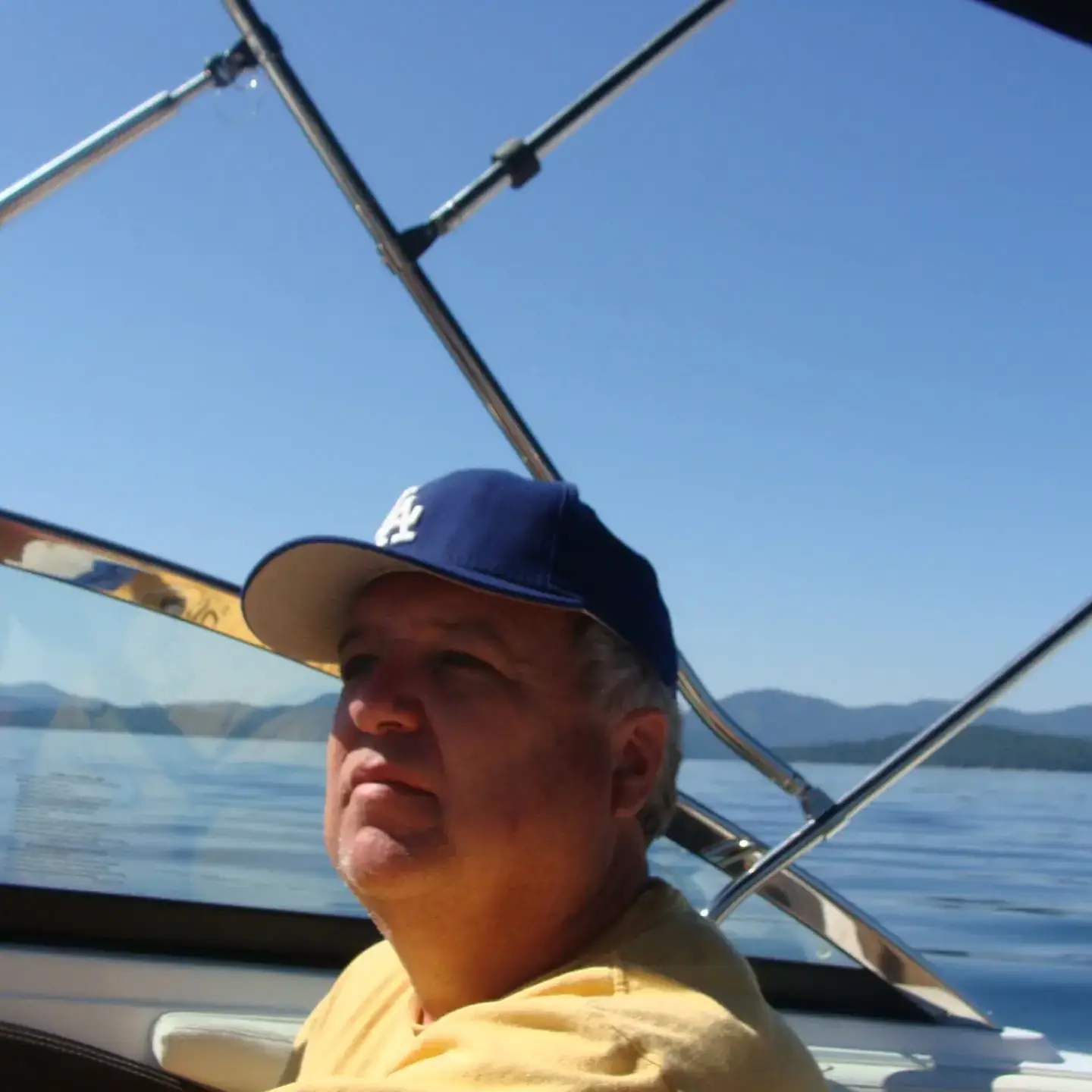 An old man sitting in a boat on the water.