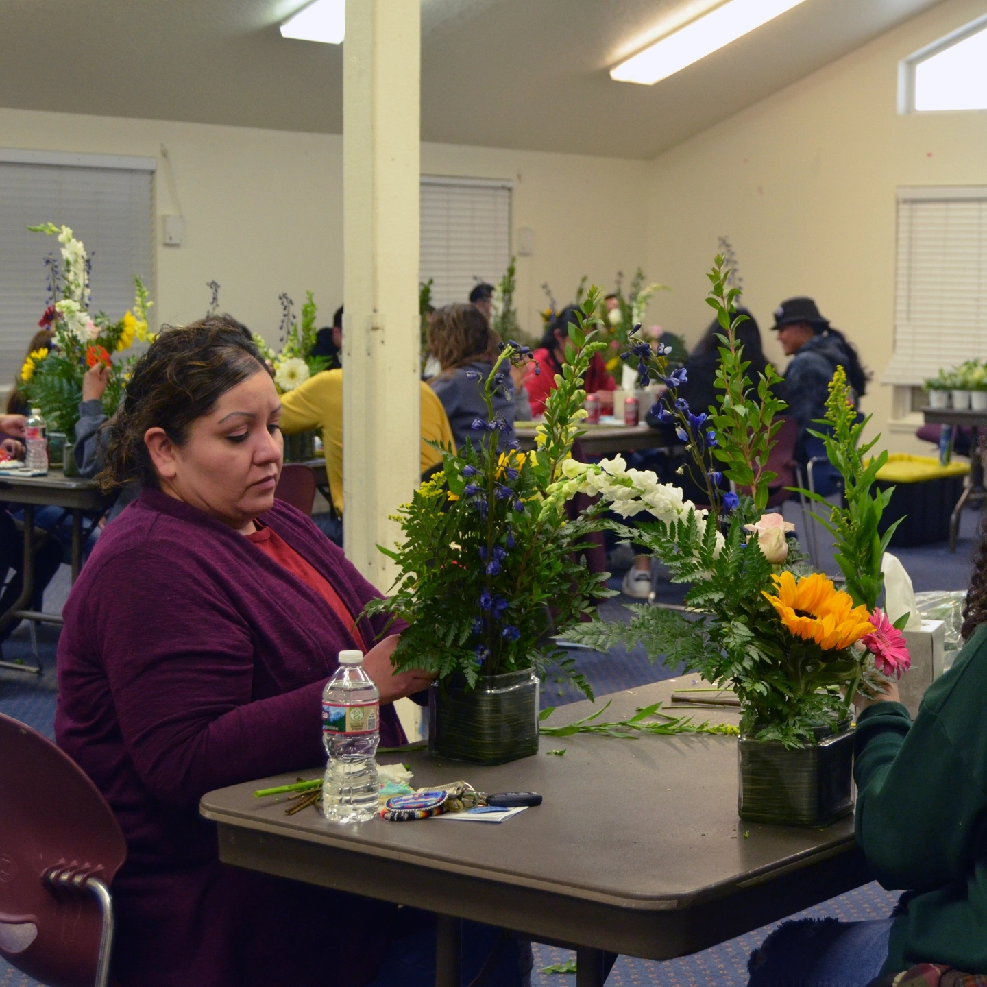 People make flower arrangements in a meeting hall.