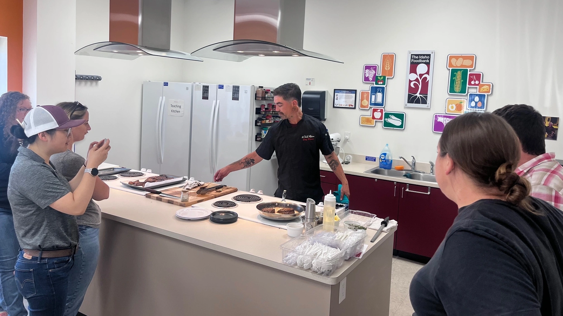 Ground beef fries in a skillet while a chef gives a crowd a cooking demonstration.