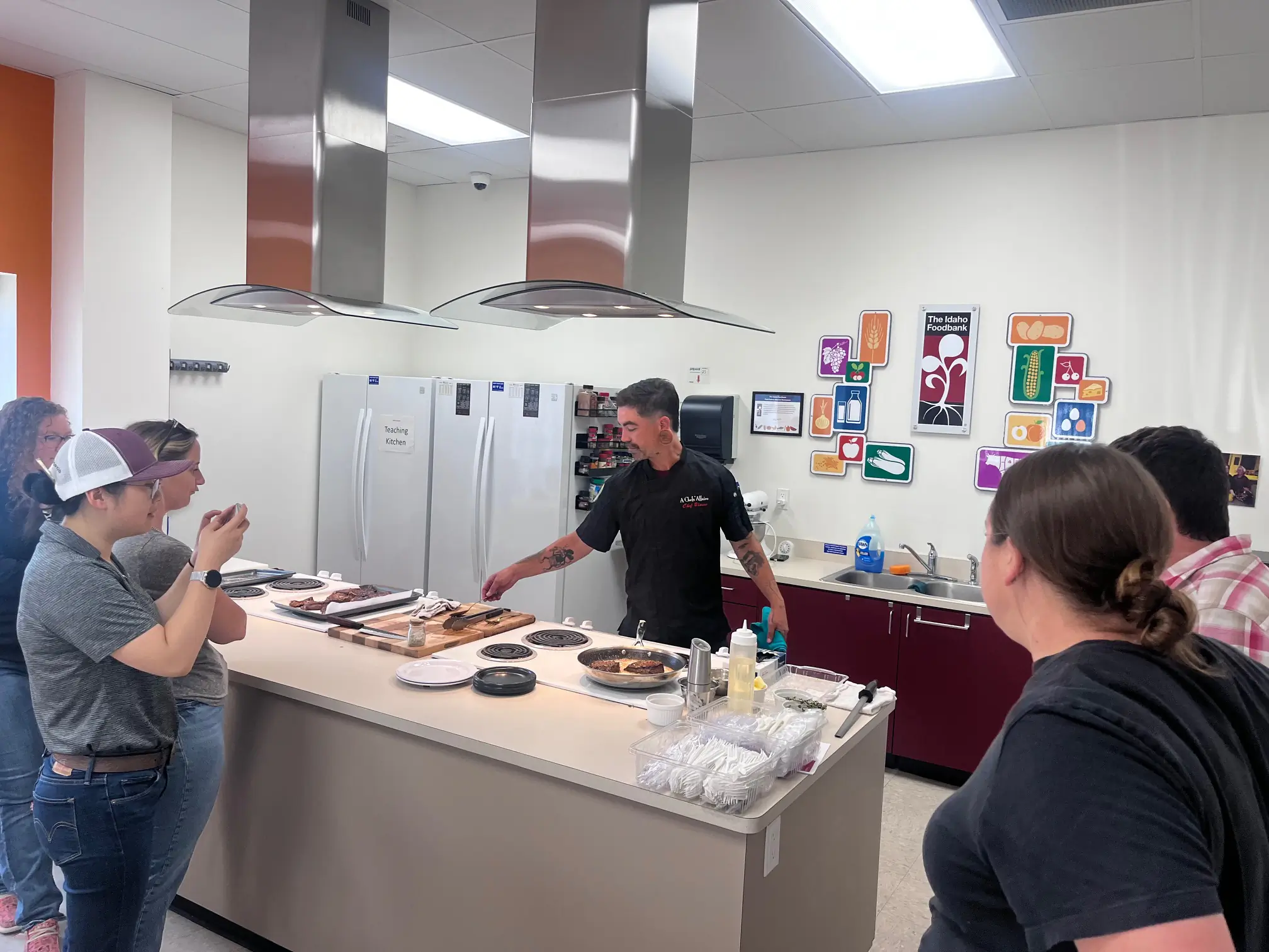 Ground beef fries in a skillet while a chef gives a crowd a cooking demonstration.