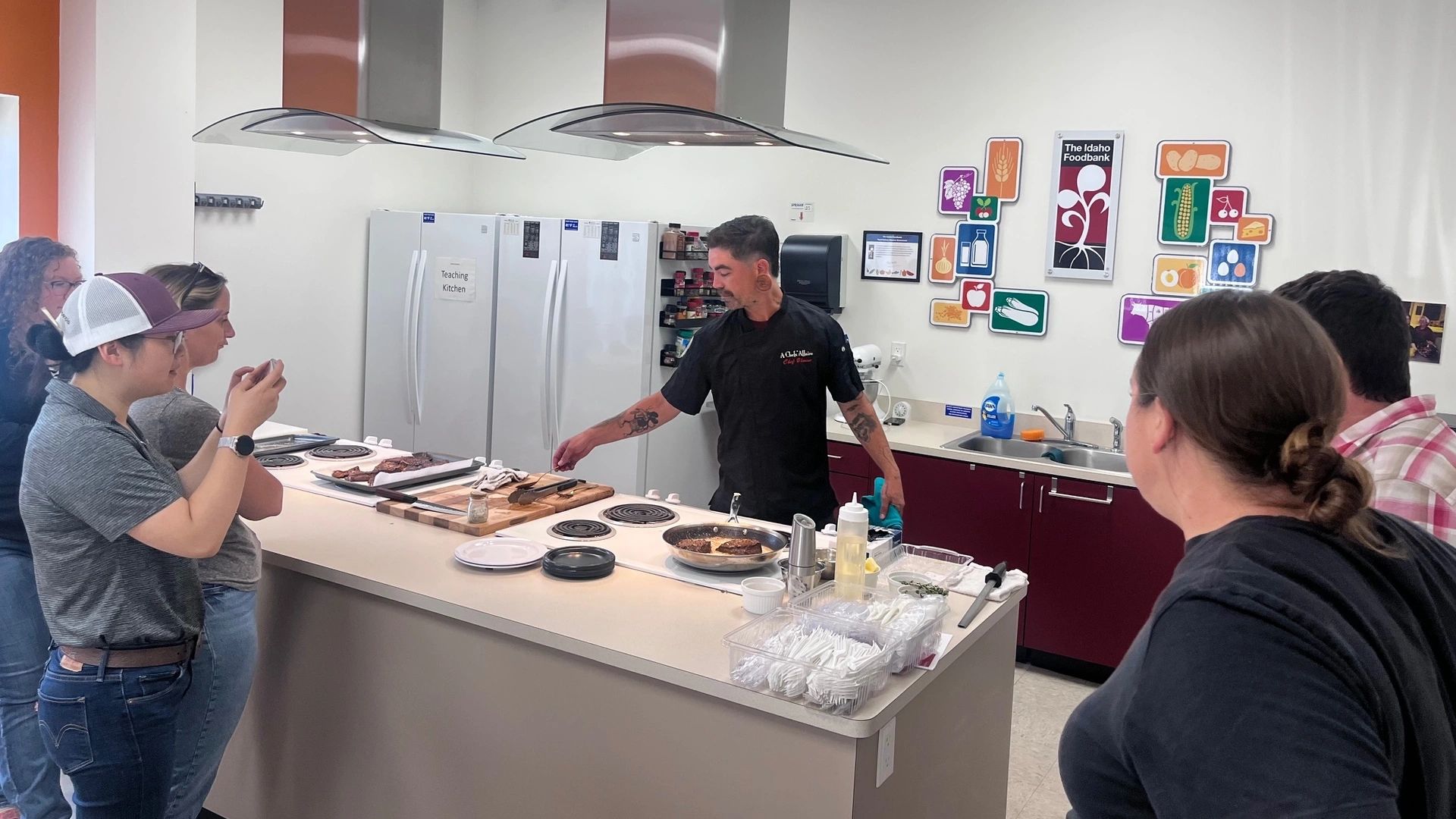 Ground beef fries in a skillet while a chef gives a crowd a cooking demonstration.