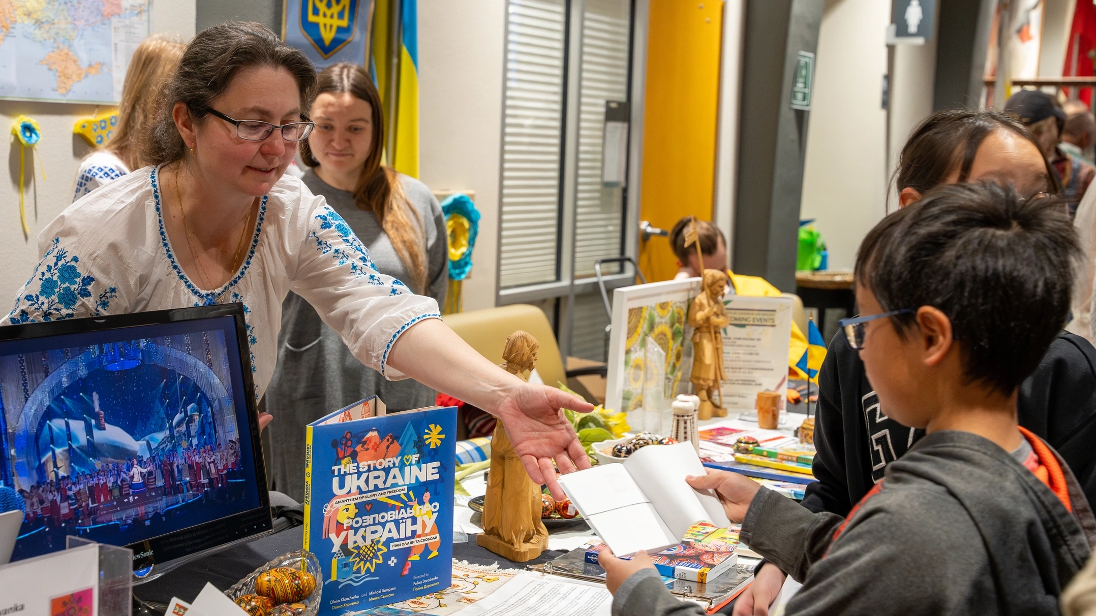 A volunteer at a booth shares books and media from her culture