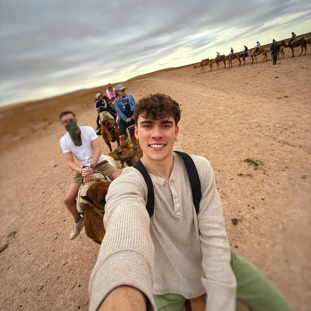 A group of people riding camels along a desert path.