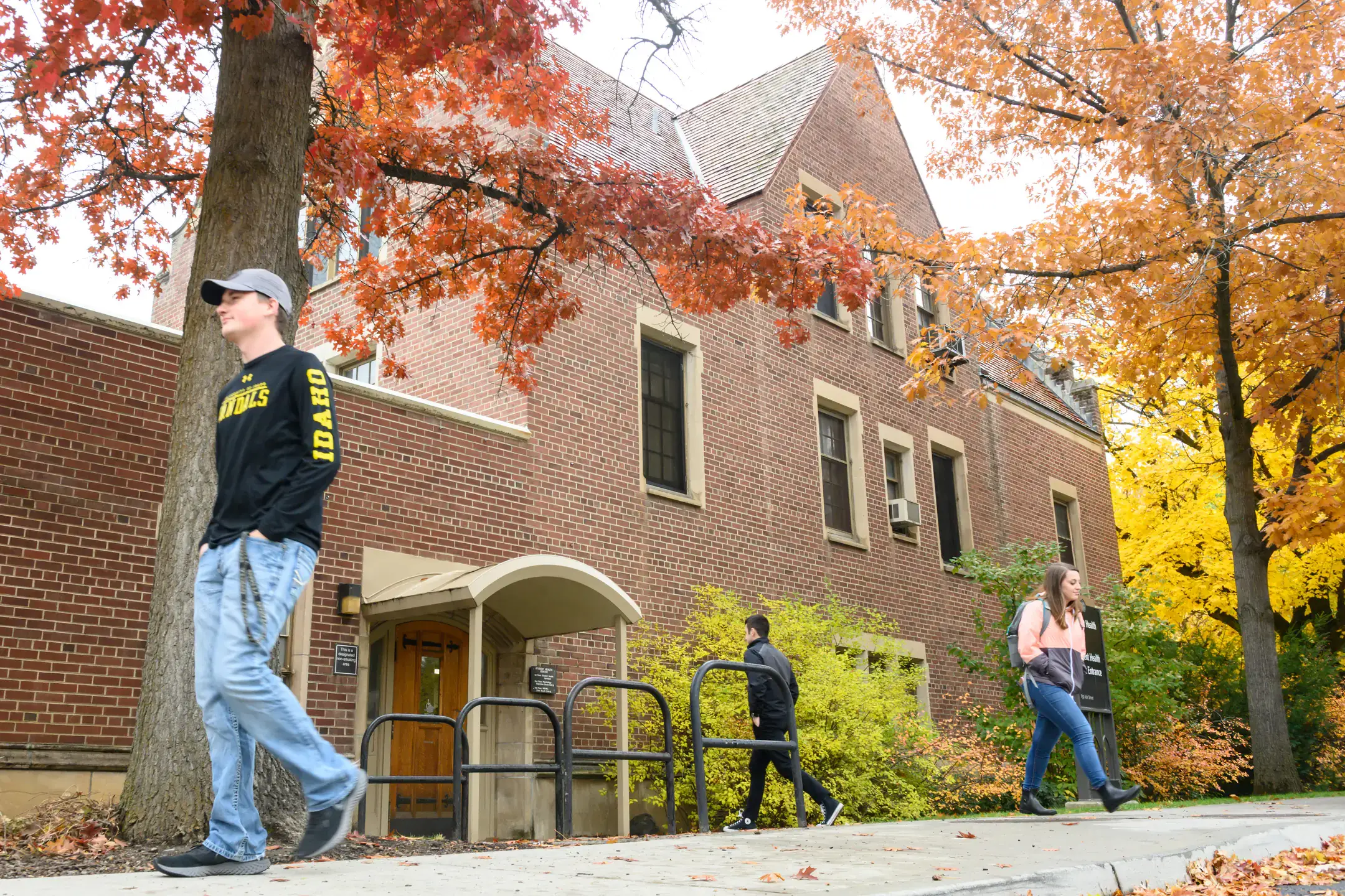 Students walking outside past a brick building