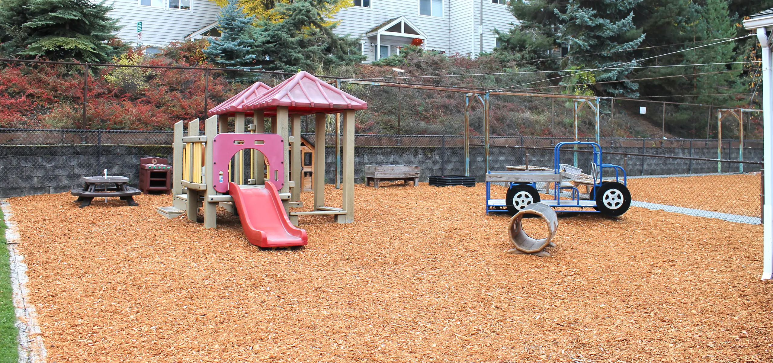 A playground with jungle gyms, slide, picnic table, and other toys.