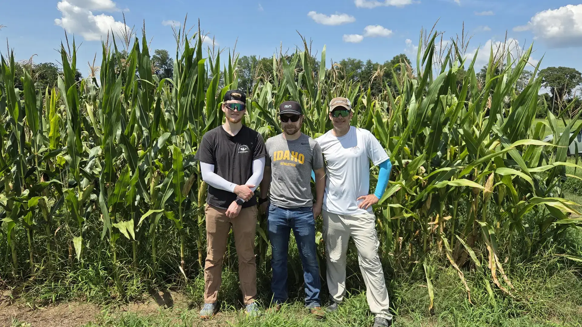 Students and faculty pose in front of a cornfield after conducting field work 