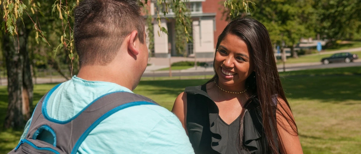 Two students talking on a lawn