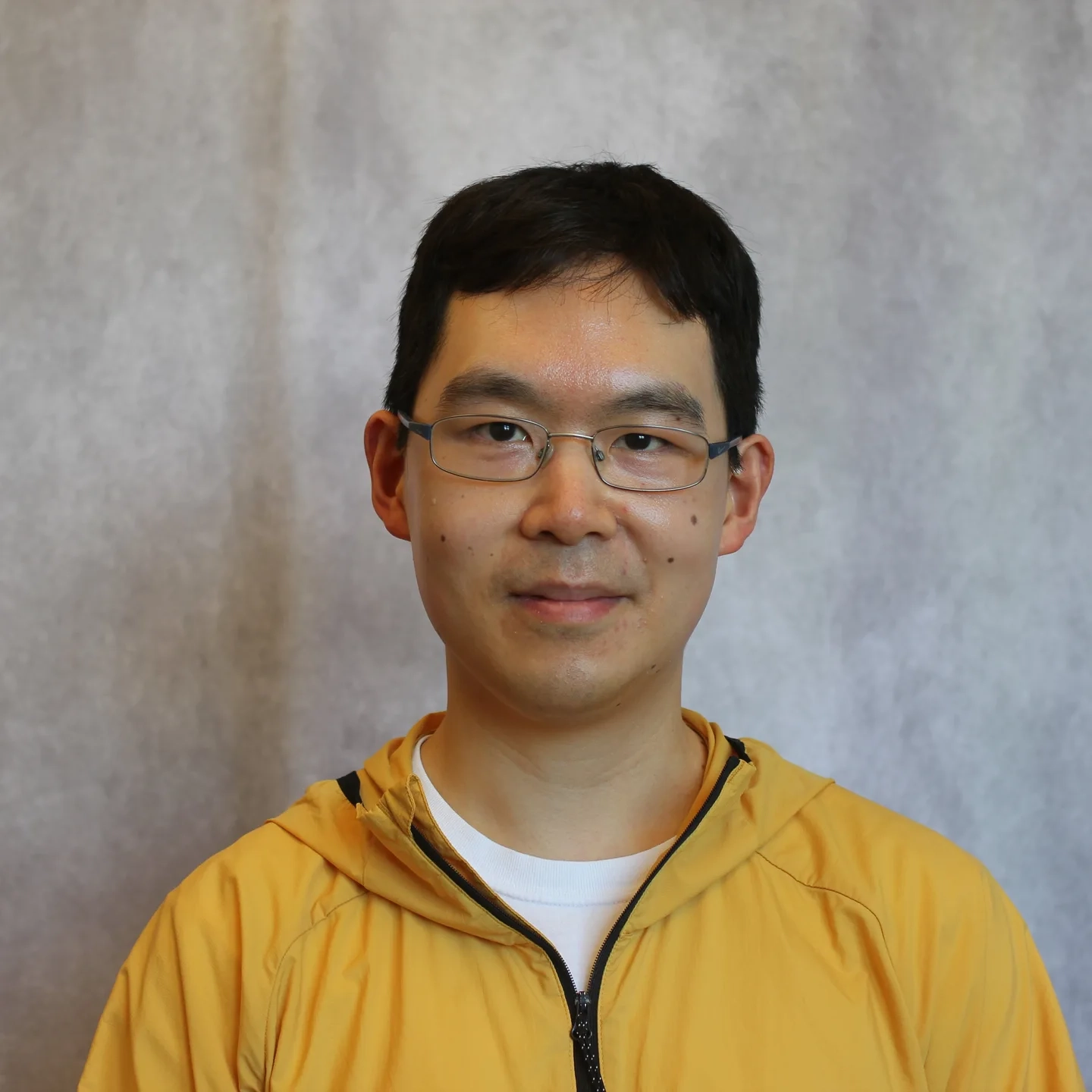 Portrait of a man standing in front of a grey backdrop.