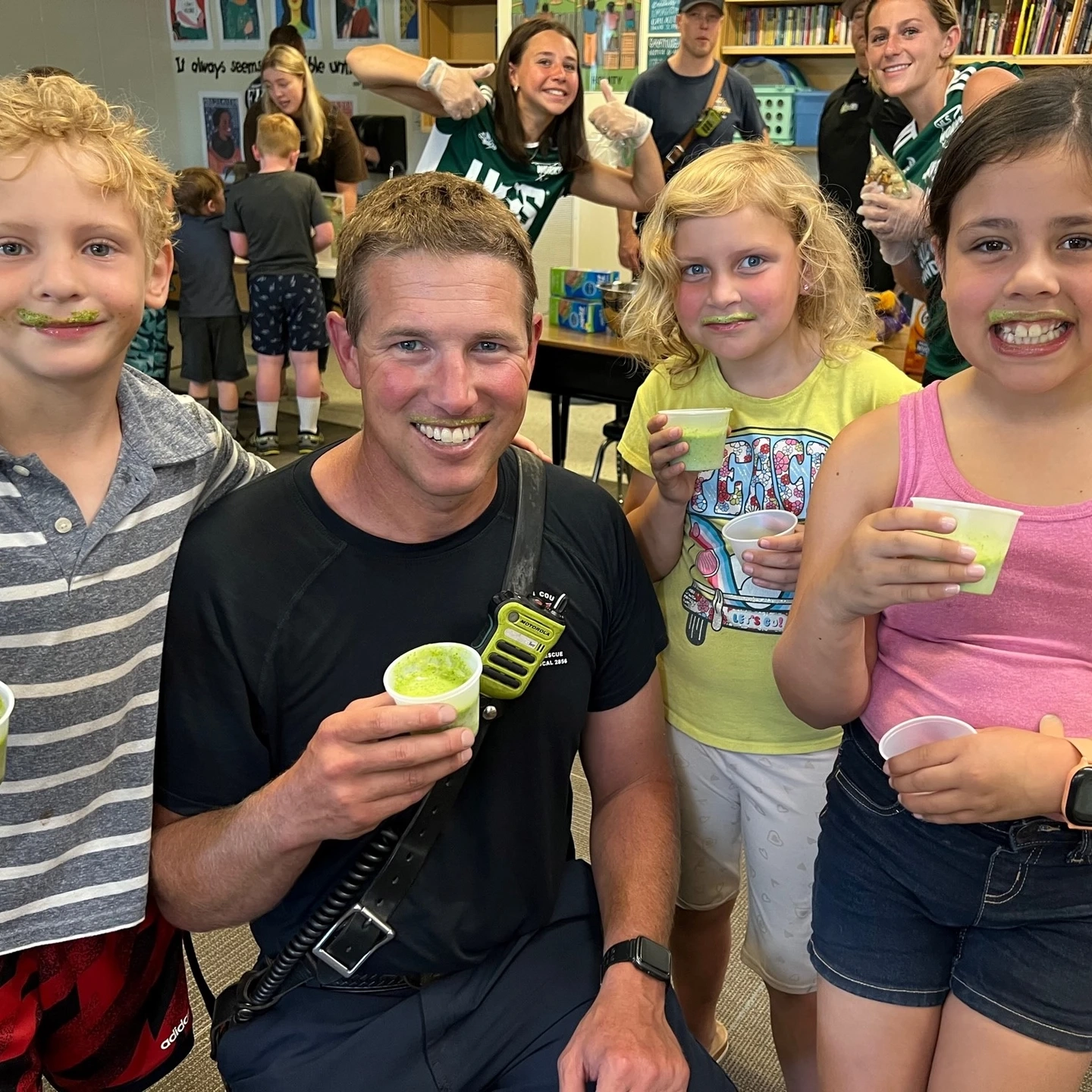 Group of children and one adult pose with smoothies.