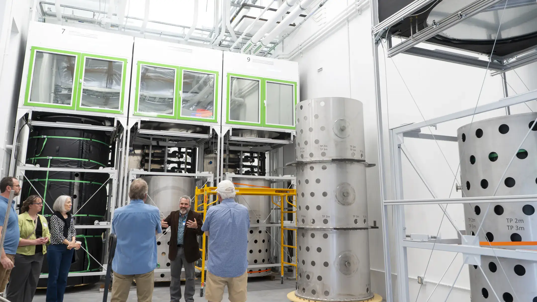 eople look at large metal cylinders that hold soil in the Deep Soil Ecotron.