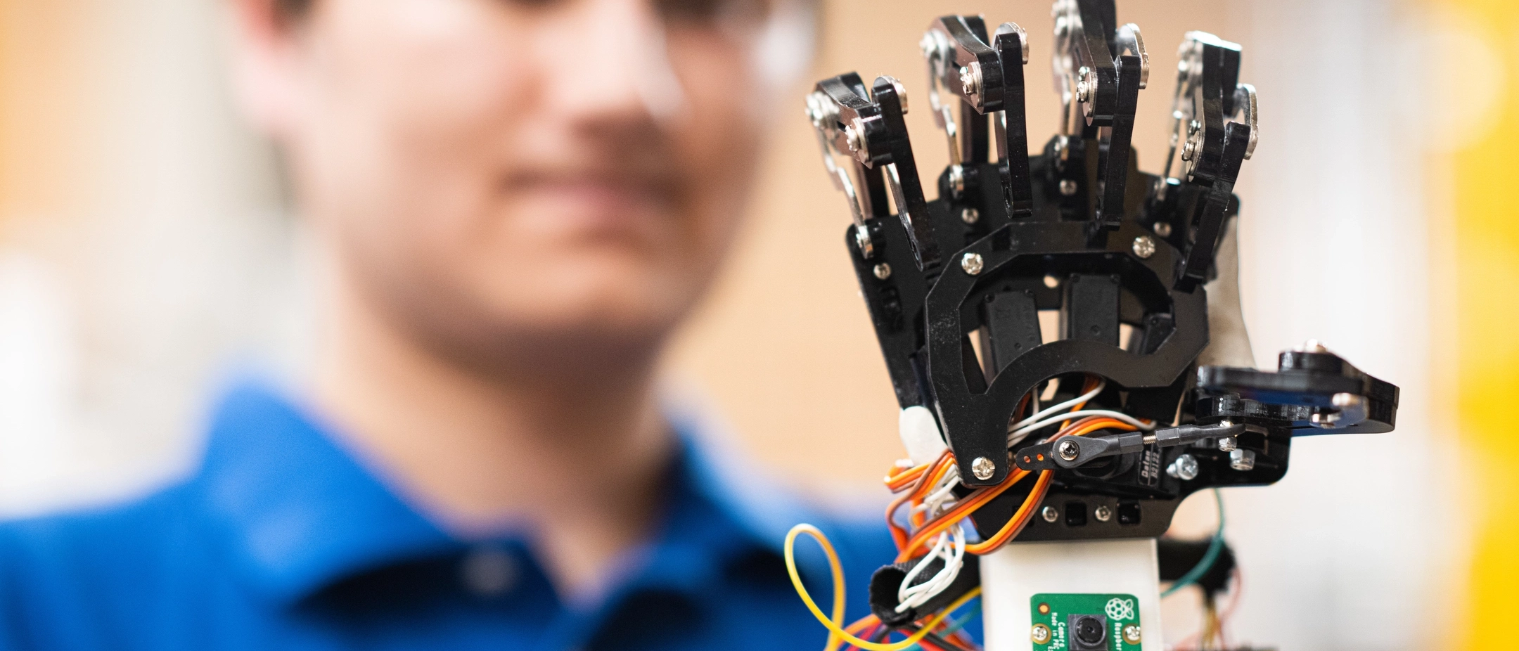 U of I student looking a a robotic hand in a classroom. 
