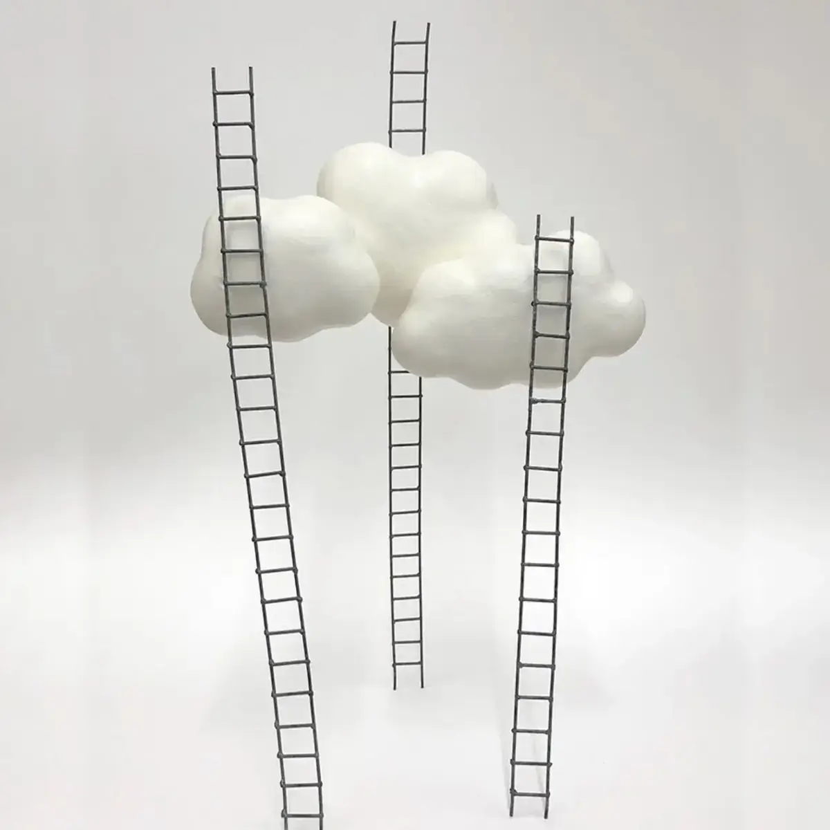 Three cloud sculptures with ladders leading up to them