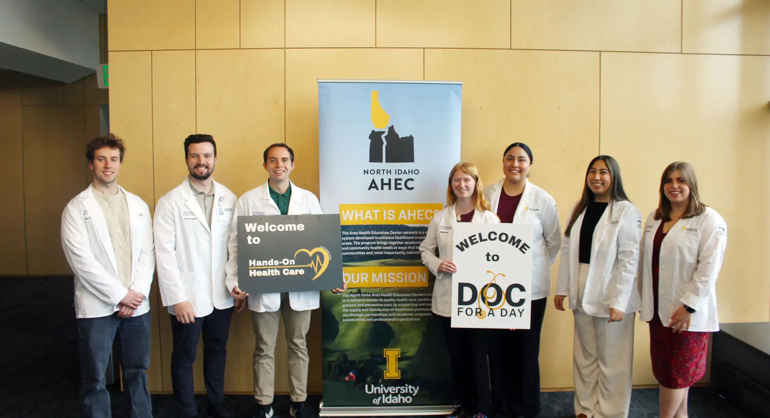 Students in white lab coats smiling for group photo